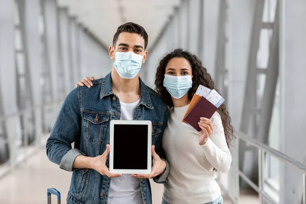 Közel-keleti pár orvosi maszkok mutató üres digitális tabletta repülőtéren — Stock Fotó