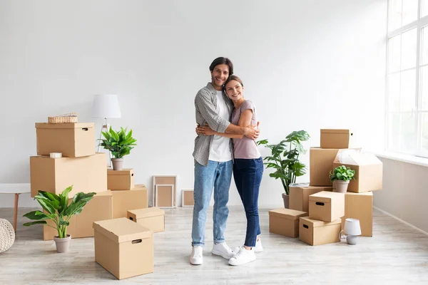 Blij jonge Kaukasische man en vrouw in casual knuffelen in kamer met kartonnen dozen, verhuur van flat en relocation — Stockfoto