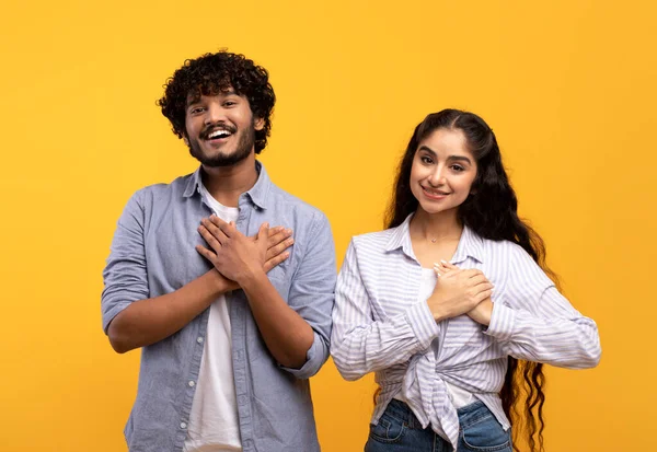 Agradecida pareja india manteniendo ambas palmas en el pecho, sonriendo a la cámara, expresando aprecio y amabilidad — Foto de Stock