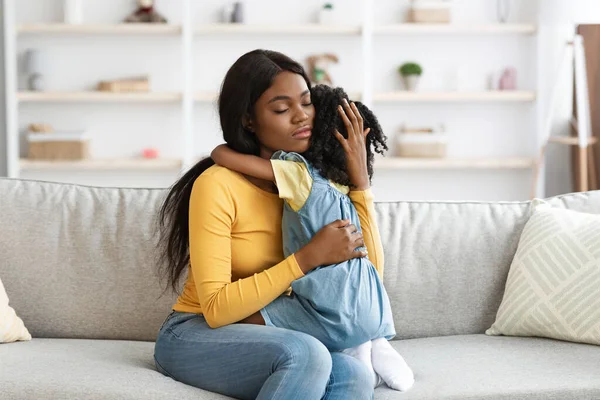 Догляд за афроамериканською мамою втішає маленьку дочку вдома — стокове фото