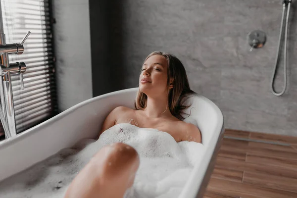 Señora pacífica disfrutando de un baño caliente con burbujas de jabón, relajarse en la bañera con los ojos cerrados después del día duro, espacio libre —  Fotos de Stock
