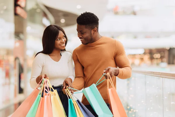 Glad svart par håller shoppingväskor tittar på varandra — Stockfoto