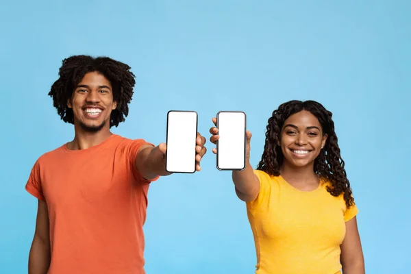 Glimlachende zwarte man en vrouw tonen mobiele telefoons, mockup — Stockfoto