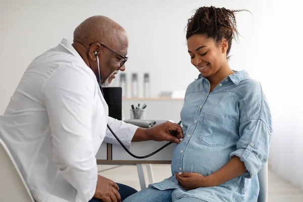 Médico experimentado masculino examinando a una mujer embarazada joven — Foto de Stock