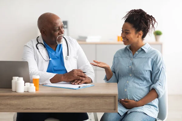 Male doctor consulting young smiling pregnant woman — Stock Photo, Image