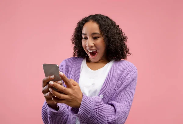 Sorprendido joven dama negra mirando la pantalla del teléfono inteligente en la emoción, ganar la lotería o la apuesta de casino en línea — Foto de Stock