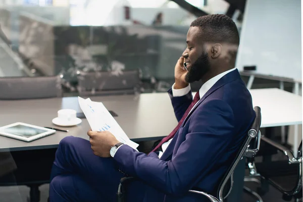 Afrykański amerykański menedżer rozmawiający przez telefon, czytający gazety — Zdjęcie stockowe