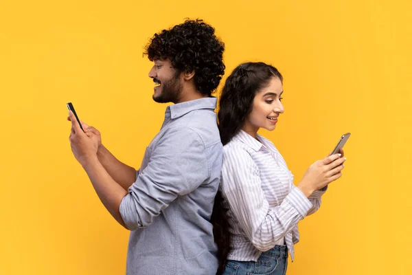 Sosyal ağ bağımlılığı. Sırt sırta verip birbirlerini görmezden gelen akıllı telefonlar kullanan genç Hintli çift. — Stok fotoğraf