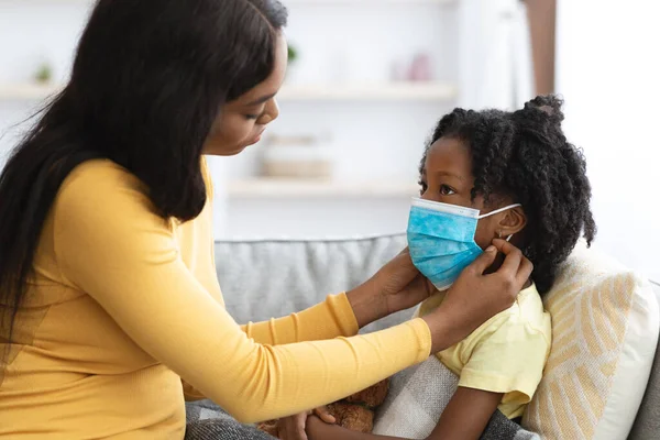Niños y Omicron. Cuidar mamá poniendo en médico máscara en enfermo hija —  Fotos de Stock