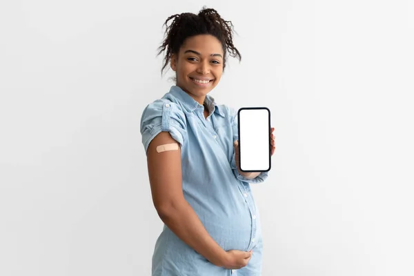 Senhora preta grávida mostrando gesso no braço e tela em branco — Fotografia de Stock