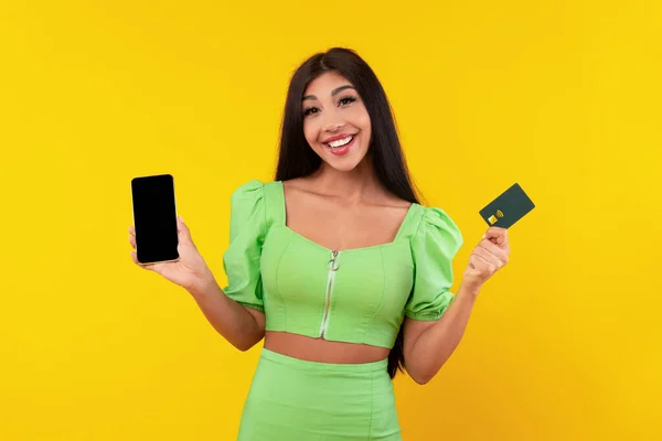 白い携帯電話の画面とクレジットカードを示す笑顔の女性 — ストック写真