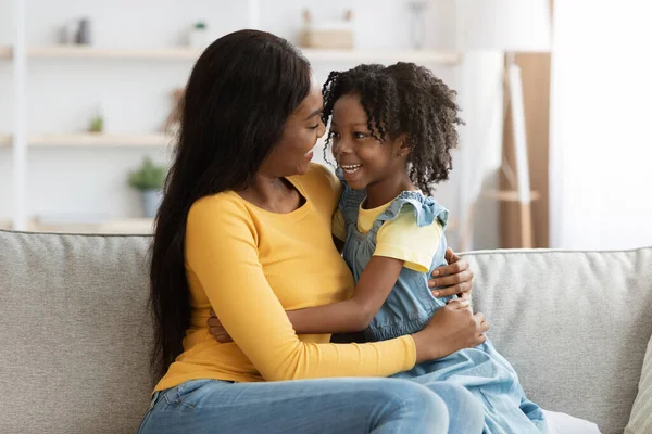 Muotokuva iloinen nuori musta nainen syleilee tyttärensä kanssa kotona — kuvapankkivalokuva
