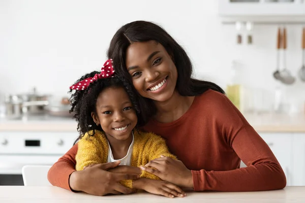 Happy Beautiful Black Mother And Her Little Daughter Posing In Kitchen Interior