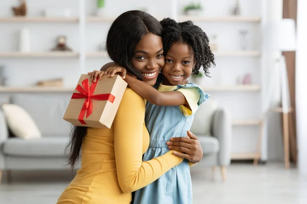 Moederdag Concept. Schattig zwart vrouwelijk kind Holding Gift en omhelzen mam — Stockfoto