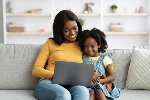 Ψηφιακός ελεύθερος χρόνος. Ευτυχισμένη μαύρη μητέρα και η μικρή κόρη χρησιμοποιώντας το φορητό υπολογιστή στο σπίτι — Φωτογραφία Αρχείου