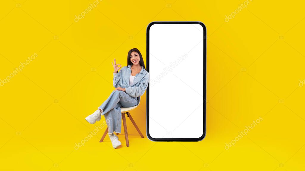 Woman with big white empty smartphone screen showing ok gesture