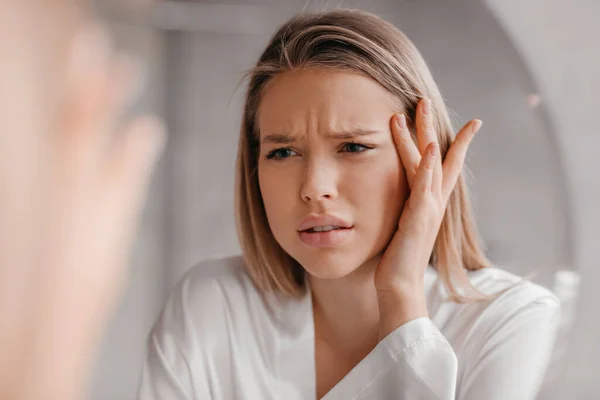 Mirror reflection of upset lady looking at mirror and touching her forehead, having dry skin problem, first wrinkles — Stock Photo, Image
