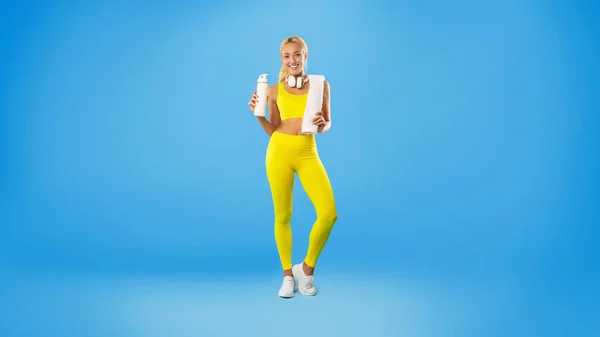 Sportowy uśmiechnięta kobieta pozowanie w studio z butelką wody — Zdjęcie stockowe