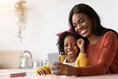 Neşeli Genç Siyah Anne ve Kız Akıllı Telefonla Birlikte Rahatlıyor