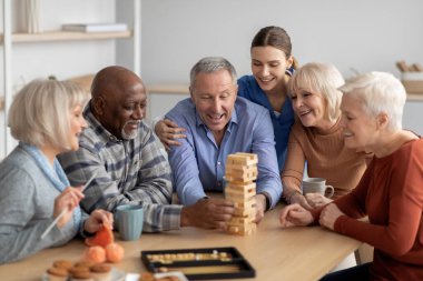 Sanatoryumda Jenga oynayan neşeli çok ırklı son sınıf öğrencileri.