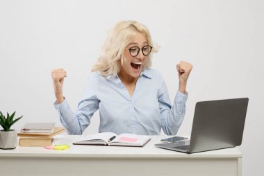 Diz üstü bilgisayar kullanan, el kol hareketi yapan, iş başarısını kutlayan, iş yerinde oturan aşırı neşeli kadın girişimci.