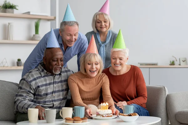 Мультиэтническая группа пожилых людей, празднующих день рождения дома — стоковое фото