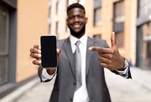 Επιχειρηματική διαφήμιση. Αφροαμερικανός επιχειρηματίας με επίσημη στολή που δείχνει το smartphone με λευκή οθόνη, mockup — Φωτογραφία Αρχείου