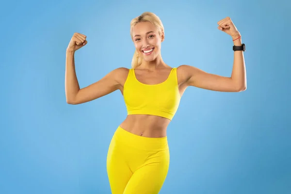 Mulher desportiva feliz mostrando músculos fortes do bíceps no estúdio — Fotografia de Stock