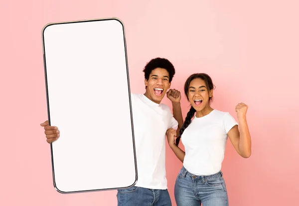Emocionada pareja negra mostrando la pantalla del teléfono inteligente blanco vacío —  Fotos de Stock
