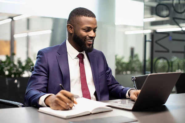 Positieve zwarte manager typen op laptop toetsenbord, notities maken — Stockfoto