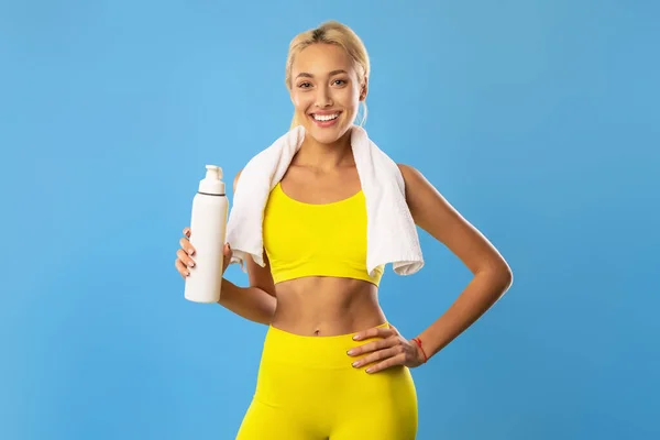 Αθλητική χαμογελαστή γυναίκα που ποζάρει στο στούντιο με μπουκάλι νερό — Φωτογραφία Αρχείου