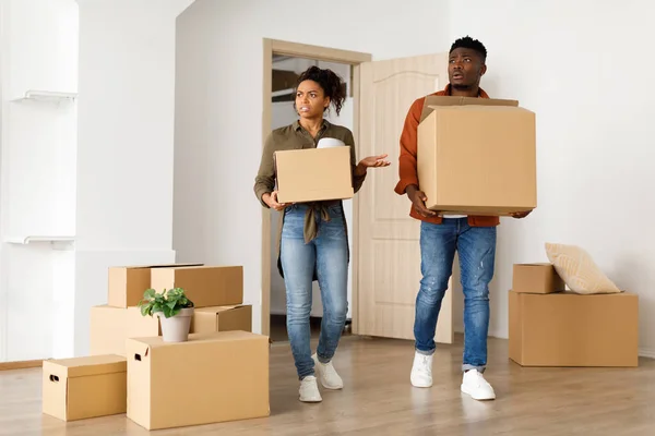 Недовольная афроамериканская пара, перевозящая коробки в помещении — стоковое фото
