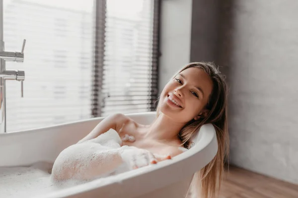 Accueil spa, hygiène, concept de détente. Portrait de femme heureuse prenant un bain à la maison, couchée dans une baignoire mousseuse, espace de copie — Photo