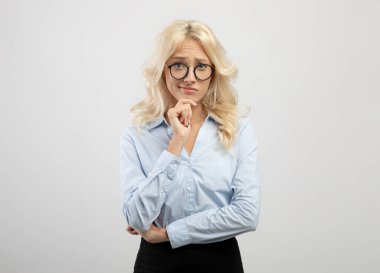 Karar veriyorum. Gözlüklü düşünceli iş kadını portresi kameraya bakıyor ve çeneye dokunuyor, açık arkaplan