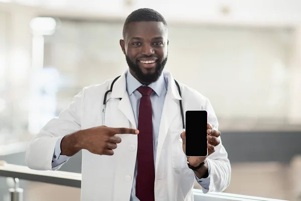 Yakışıklı Afrikalı Amerikalı doktor akıllı telefonu işaret ediyor, maket. — Stok fotoğraf