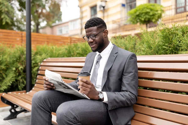 Αυτοπεποίθηση αφροαμερικανός επιχειρηματίας διαβάζοντας καθημερινά νέα στην εφημερίδα και πίνοντας καφέ για να πάει, κάθεται στον πάγκο — Φωτογραφία Αρχείου