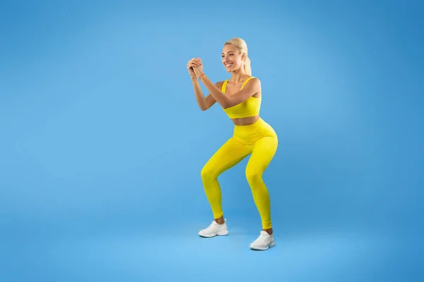 Uśmiechnięta młoda kobieta robi głębokie Squat ćwiczenia — Zdjęcie stockowe