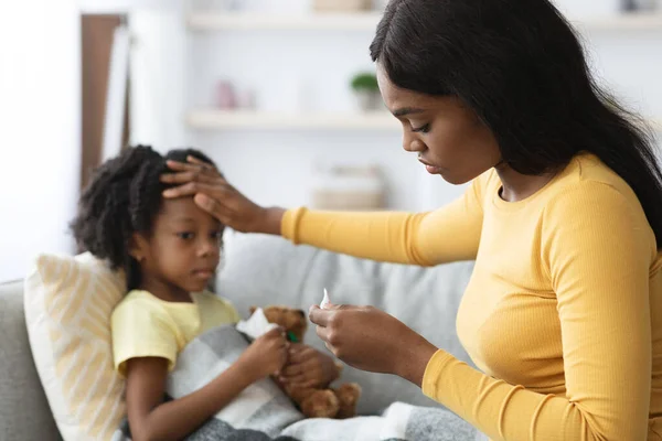 心配アフリカ系アメリカ人の母親彼女の病気の女性の子供の温度をチェック — ストック写真