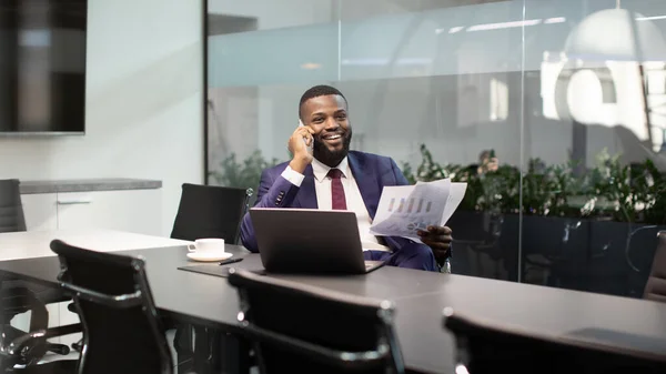 Sonriente jefe negro tener conversación telefónica en la oficina, la celebración de documentos — Foto de Stock