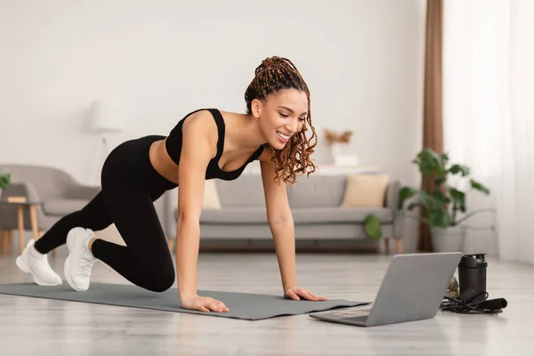 Mujer cerca de la computadora portátil haciendo Plank Ejercicio de entrenamiento en casa — Foto de Stock