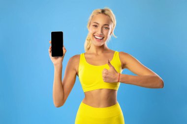 Mutlu sportif kadın cep telefonunu boş ekranla gösteriyor.