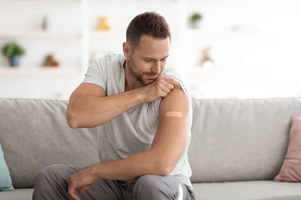 Covid-19 vaccinatie. Jonge vrolijke blanke man met schouderpleister na vaccinatie, lege ruimte — Stockfoto