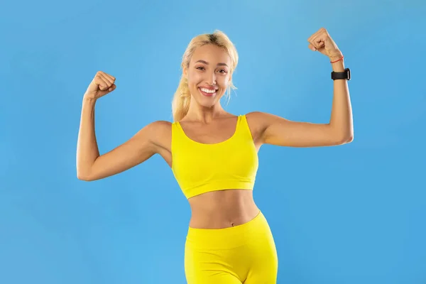 Mujer deportiva feliz mostrando fuertes músculos del bíceps en el estudio — Foto de Stock