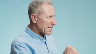 Umutsuzluk konsepti. Umutsuz, yaşlı, gri saçlı, yumruğunu ısıran, umutsuzluğunu ifade eden, boş alana bakan bir adam.