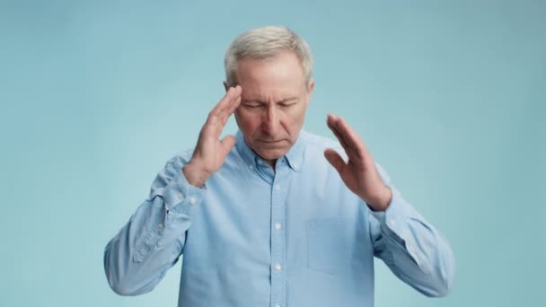 Мигрень и проблемы со здоровьем. Недовольный пожилой человек, страдающий острой головной болью, массируя свои болезненные виски — стоковое видео
