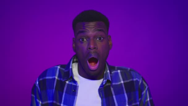 Σοκαρισμένος Αφροαμερικανός που ανοίγει το στόμα του πάνω από μωβ φόντο — Αρχείο Βίντεο