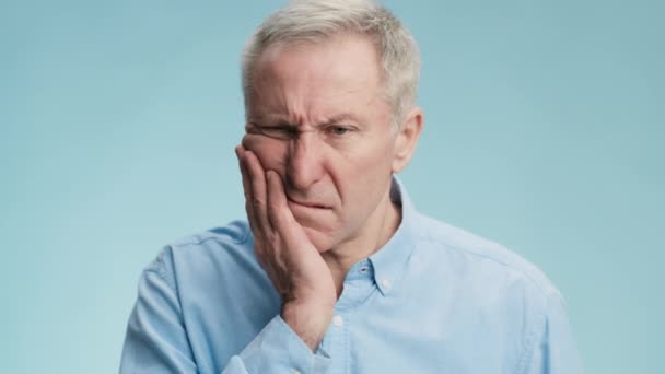Envelhecimento e problemas dentários. Homem idoso perturbado que sofre de dor aguda nos dentes, tocando sua mandíbula dolorosa e franzindo a testa — Vídeo de Stock
