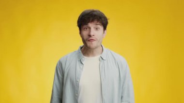 Heyecan ve destek. Genç mutlu adam yüksek sesle bağırıyor ve zıplıyor, favori spor takımı için tezahürat yapıyor, sarı arka plan