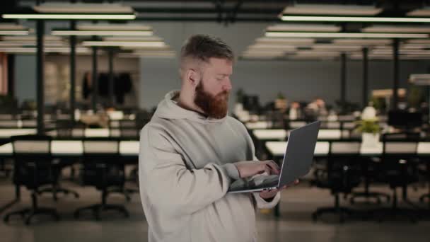 Homme barbu à l'aide d'un ordinateur portable travaillant sur ordinateur debout au bureau — Video