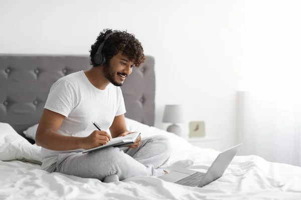 Millennial facet uczestniczy webinar z domu, za pomocą laptopa w łóżku — Zdjęcie stockowe